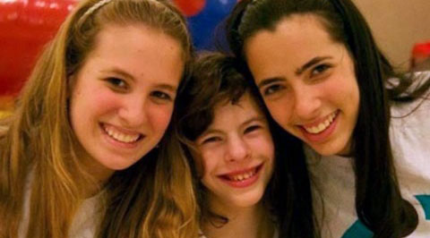 Imagem com duas voluntárias do Friendship e uma criança deficiente.