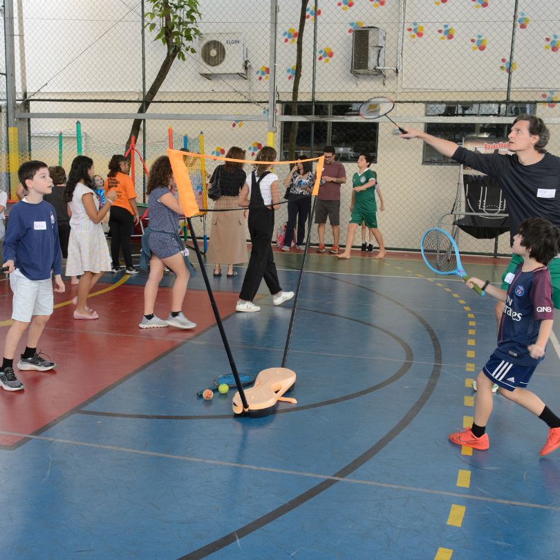 Homem segurando uma raquete de tênis, preparado para jogar em uma quadra esportiva.