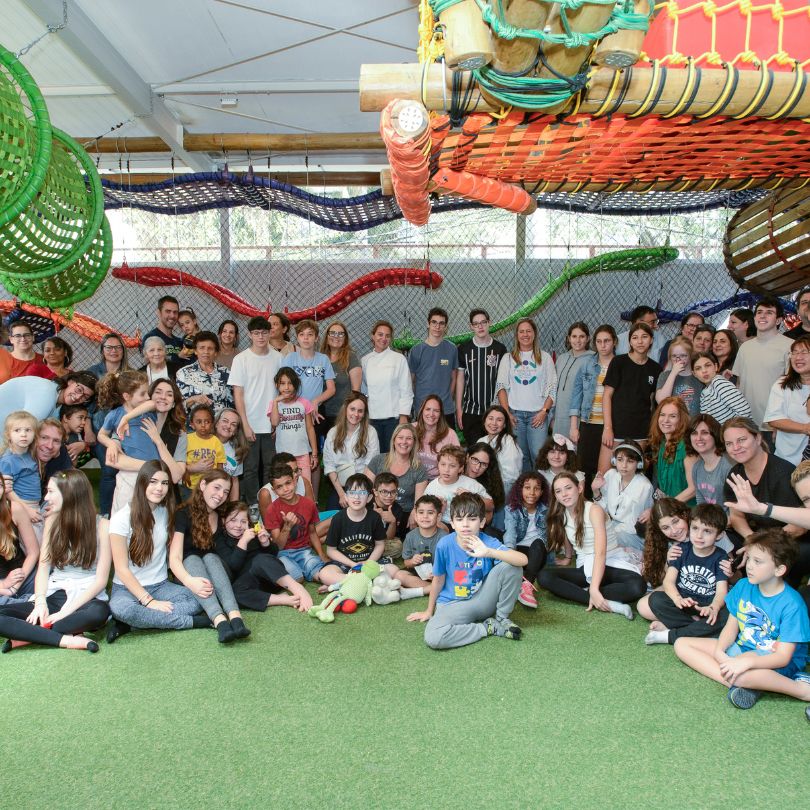 Grupo de pessoas sorrindo e posando para uma foto em um ambiente descontraído.