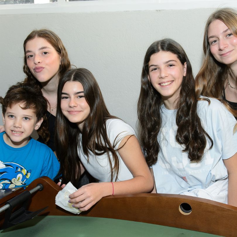 Grupo de pessoas sorrindo e posando para uma foto em um ambiente descontraído.